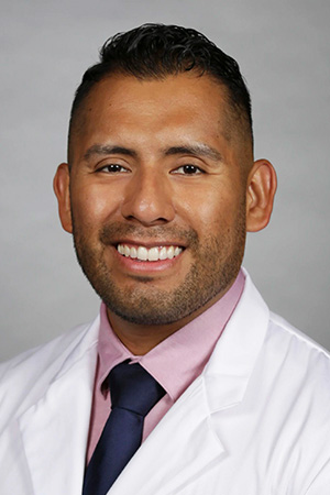 Portrait of medical student Hector Sanchez-Perez in white coat and smiling