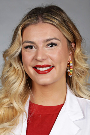 Portrait of medical student Shea Bertolucci in white coat and smiling