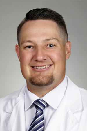 Portrait of medical student Noah Lyndall in white coat and smiling