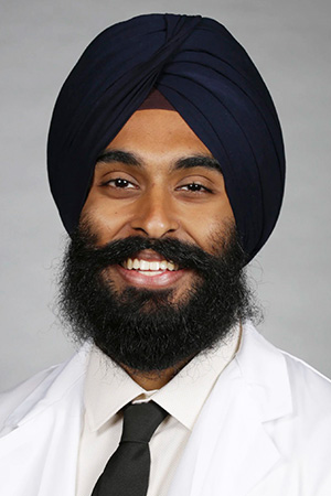Portrait of medical student Sukhdev Mann in white coat and smiling