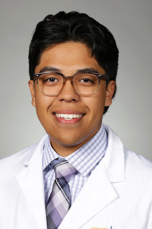 Portrait of medical student Angel Benitez-Melo in white coat and smiling