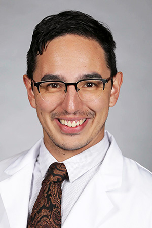Portrait of medical student Andres Ramos in white coat and smiling