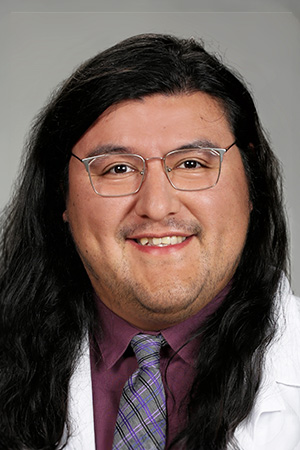 Portrait of medical student Greg Gurrola in white coat and smiling