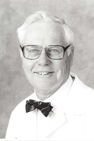 Black-and-white portrait of F. William Blaisdell wearing a white lab coat and bow tie, photographed against a neutral studio background.