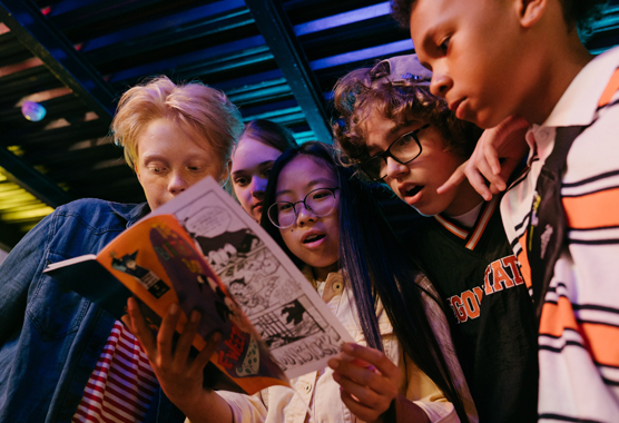 children looking at a comic book in an arcade
