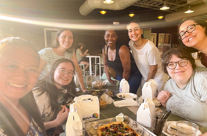 A group of people smiling and enjoying pizza and bonding