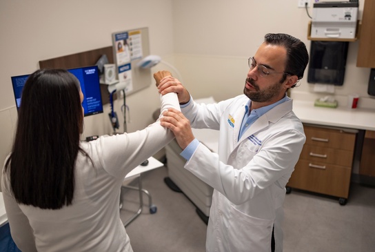 orthopedic doctor examining female patient's arm