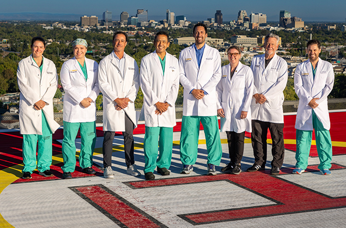 Trama Surgery Team. Eight dcotors standing on a helipad wearing lab coats. 
