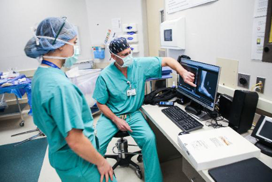 Doctor pointing at a foot xray with a resident in the OR room 