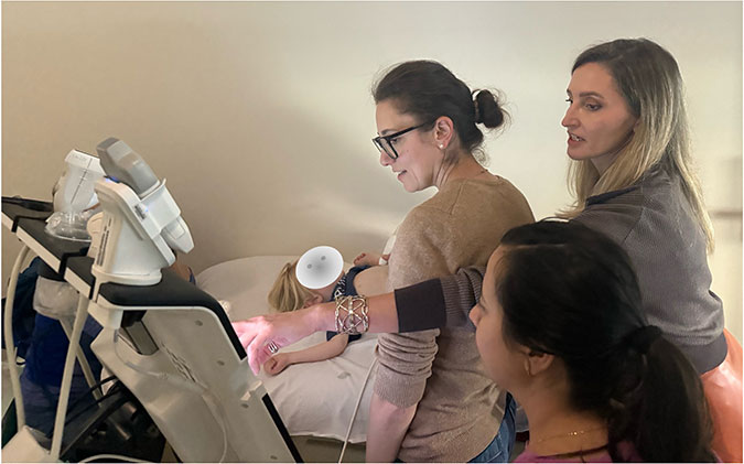 POCUS Training with instructor and student, student scanning live patient and instructor pointing to scan screen for details and analysis