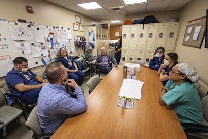 Conference attendees sit around rectangular table and discuss improvements.