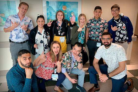 Medical clerkship students pose for fun in hospital hallway wearing Hawaiian shirts.