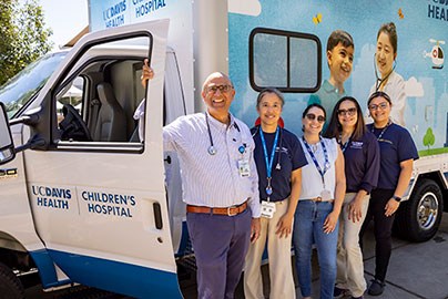 Remote travel clinc van with 5 staff posing next to van.