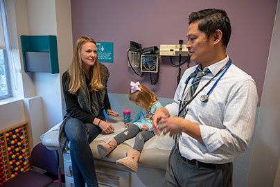 Physician and pediatric patient in exam room with her mother