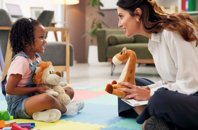 Child sitting on the ground and playing with therapist 