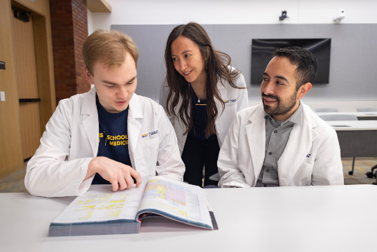 Students sitting together looking at a textbook
