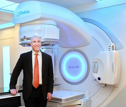 Richard Valicenti stands in front of an Elekta Versa HD linear accelerator used for patient treatments