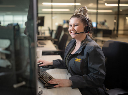 UC Davis Health contact center employee wearing a headset and seated at a computer workstation in an office, providing customer support.