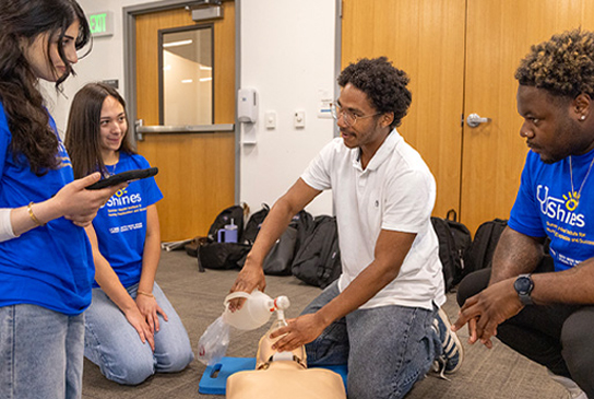Students gather around a simulation mannequin.